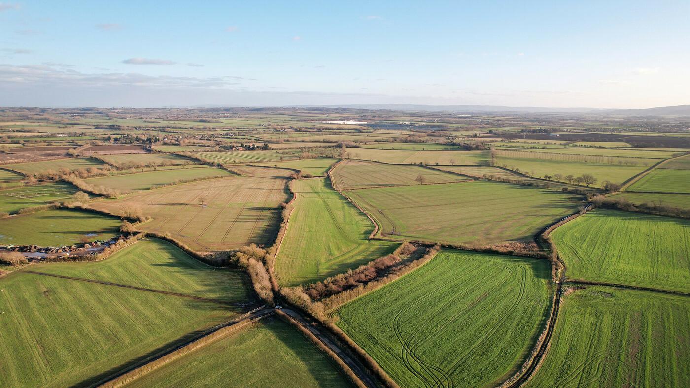 Aerial view of fields and hedgerows at Naunton Beauchamp in autumn sunshine with a blue sky