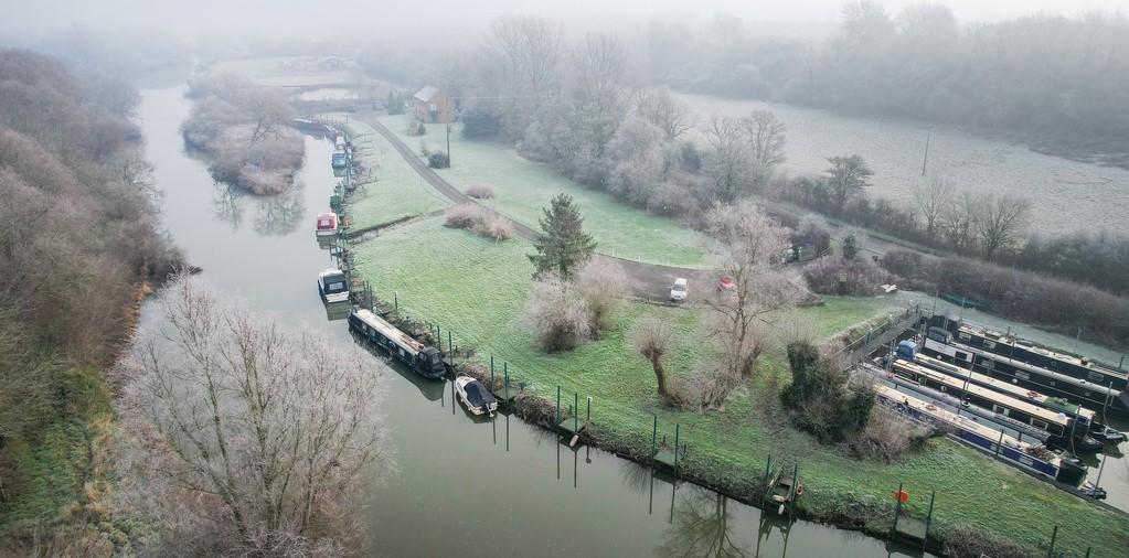 An aerial photo of the River Avon with narrowboats moored along it, lined with trees and grassy areas
