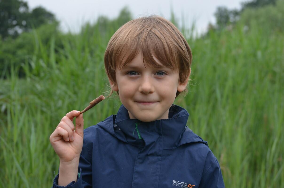 A young boy holding pond weed during survey at BioBlitz event in the Forest