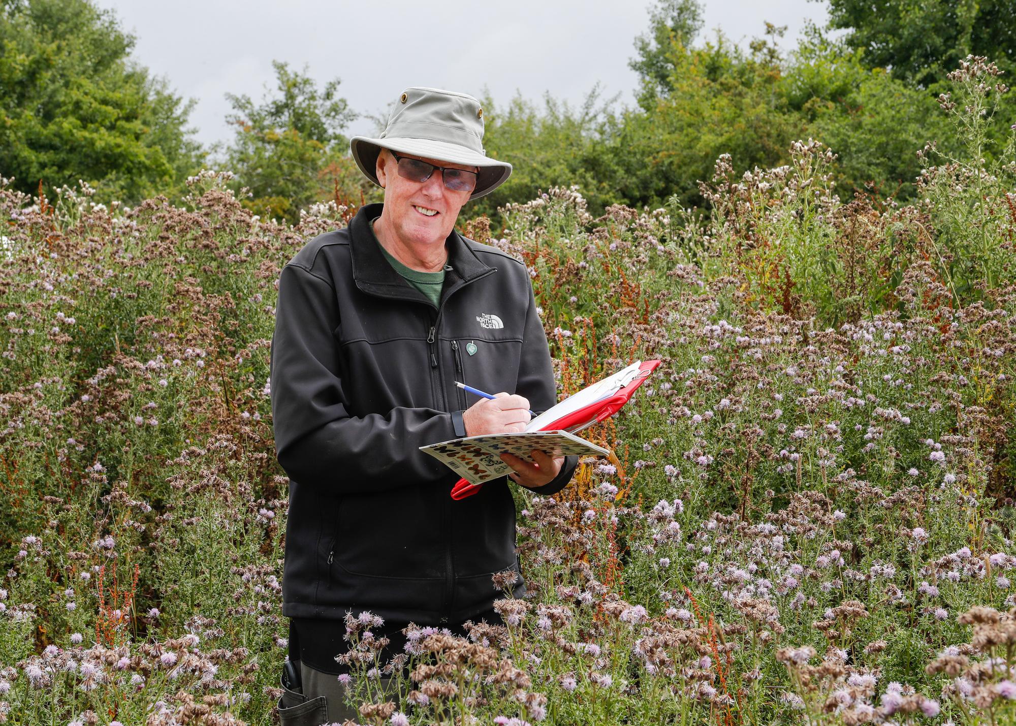Ramsay, a Volunteer Leader conducting a butterfly survey in Morgrove Coppice. He is holding a form and Butterfly ID guide