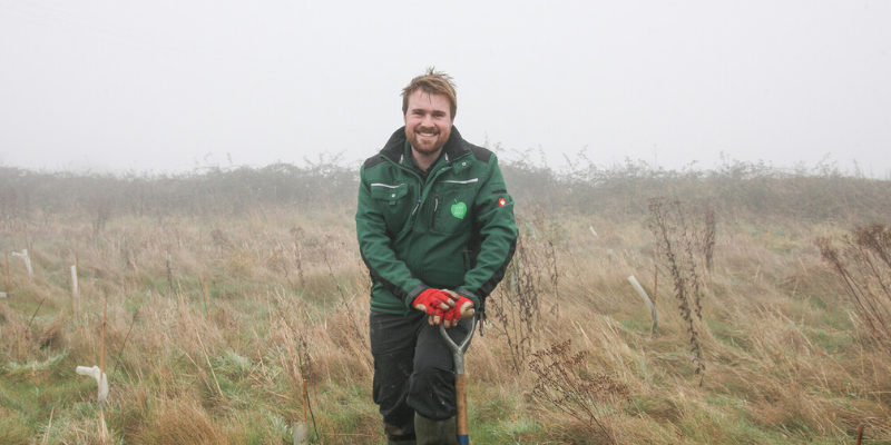 Volunteer Manager, Jonathan standing in a field with a spade in November.