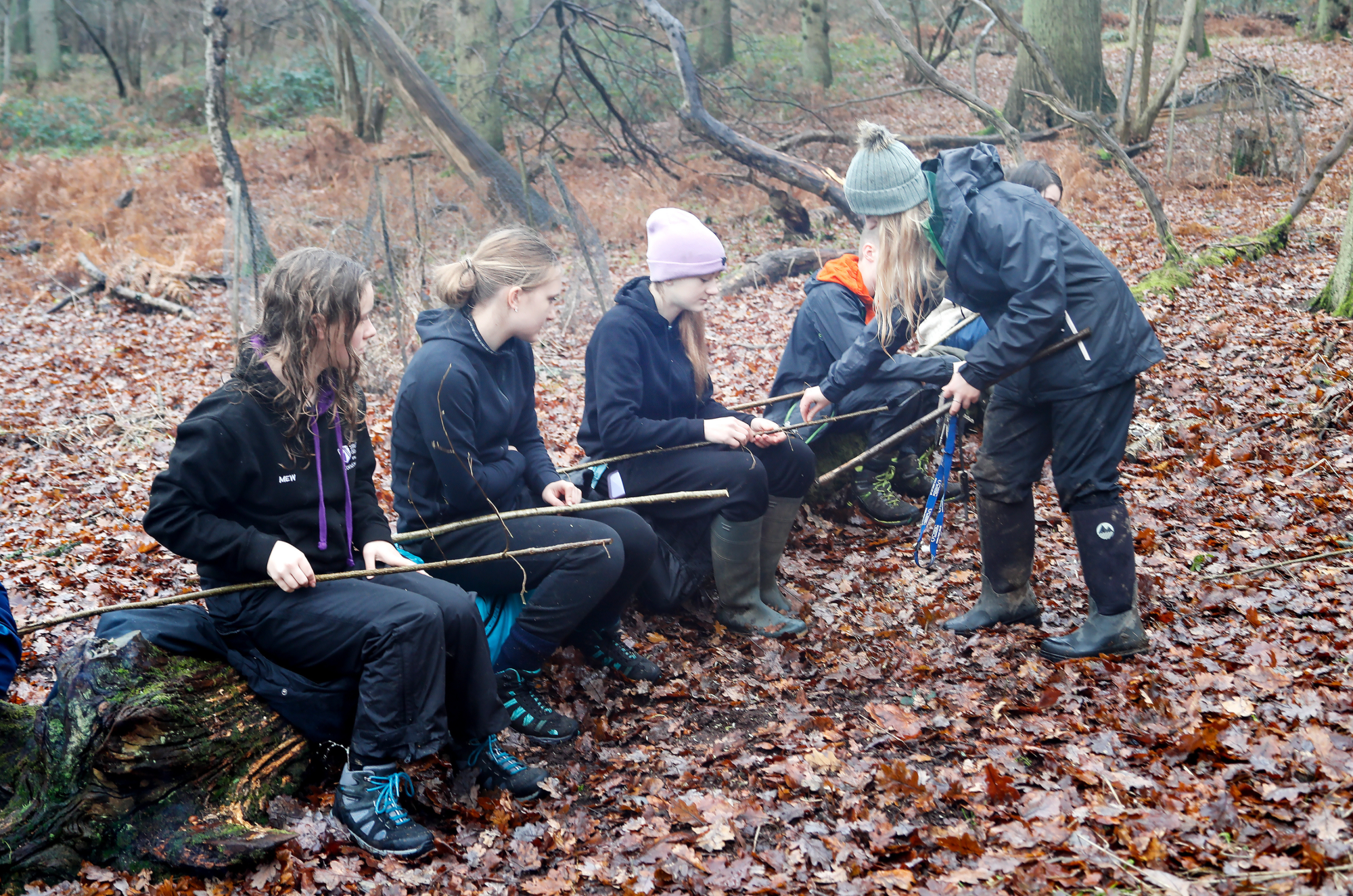 A group of young foresters sitting on a log in the forest