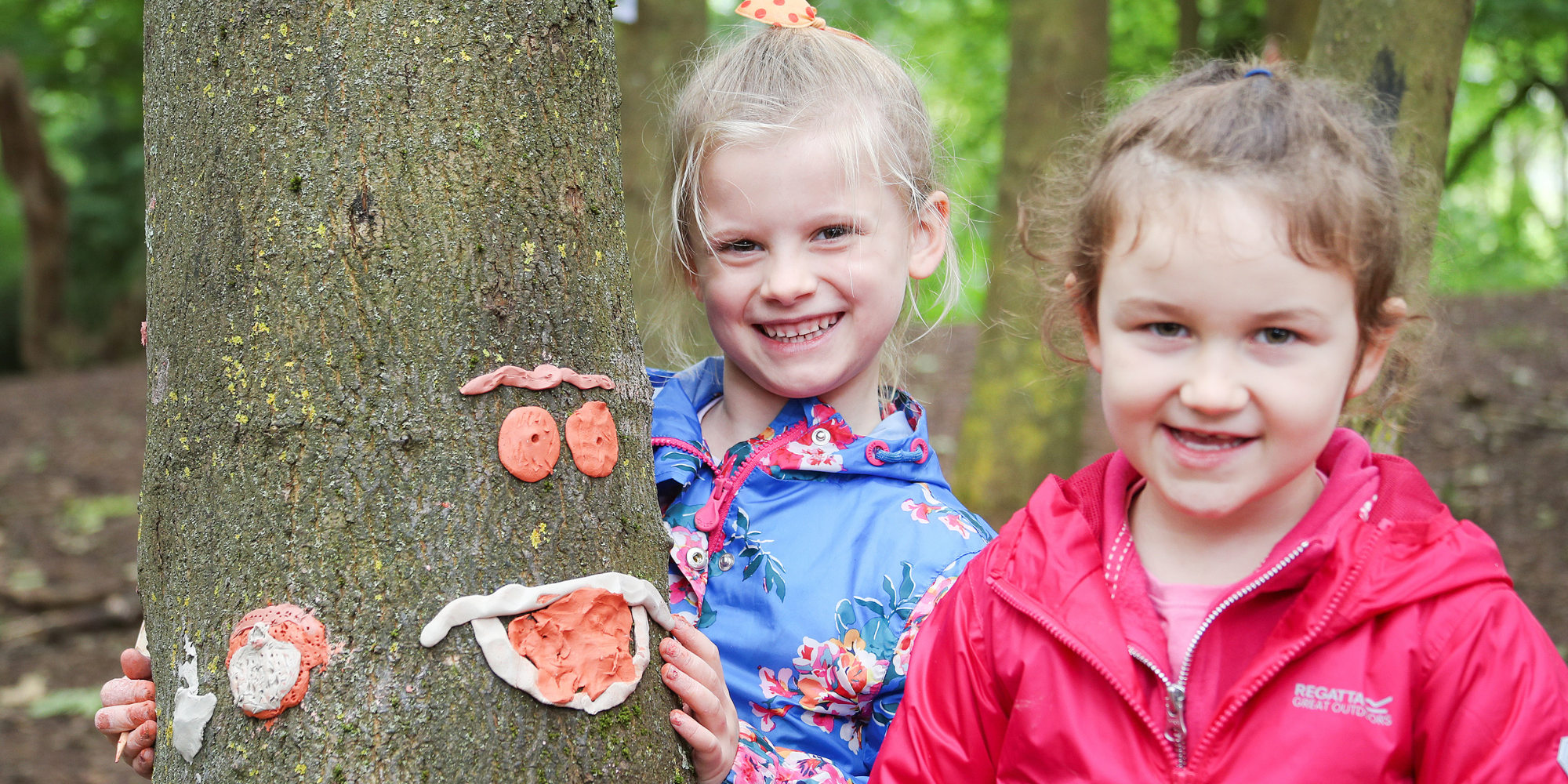 A couple of Wildtribe children creating faces on trees with art materials.