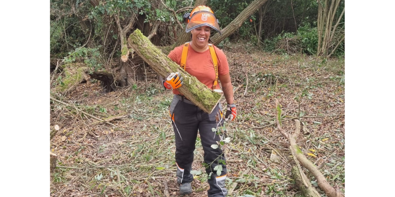 A female member of the forestry team carrying cut timber in the Forest.