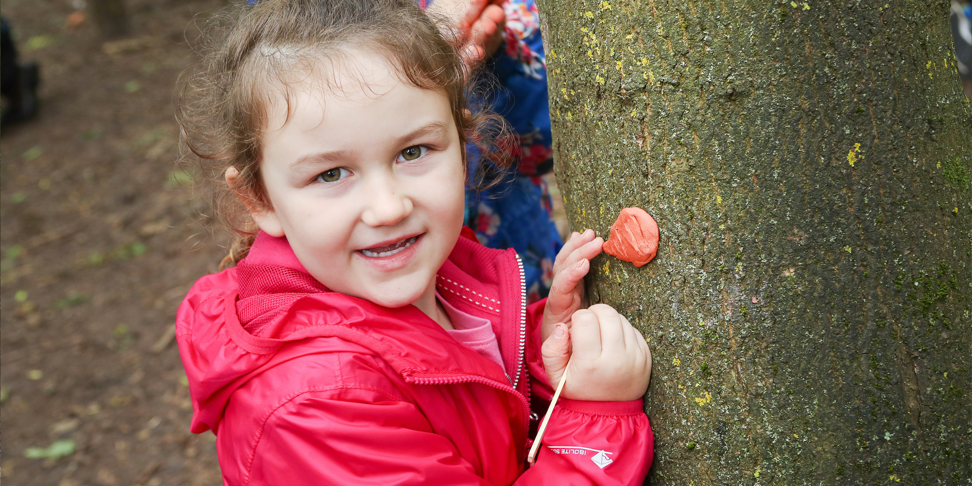 A close-up of a young child having fun with crafts in the woods