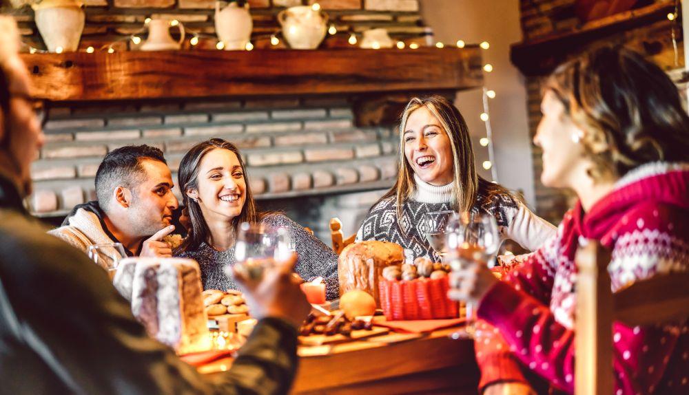 A group of friends sitting around a table in a pub wearing christmas jumpers