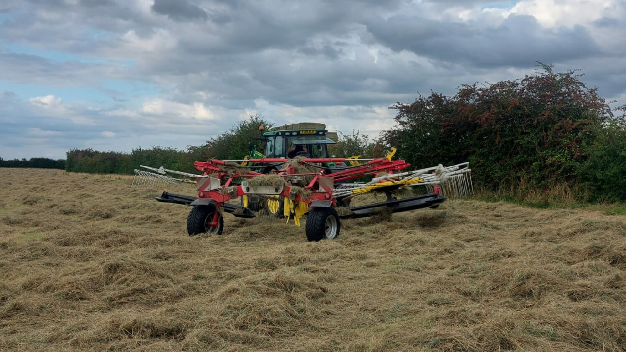 A tractor with agricultural machinery attached in order to make hay bales