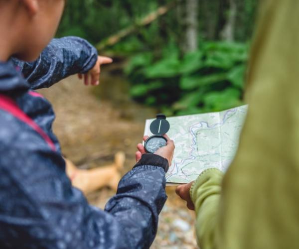 Close up of two people using a compass and map to navigate their route