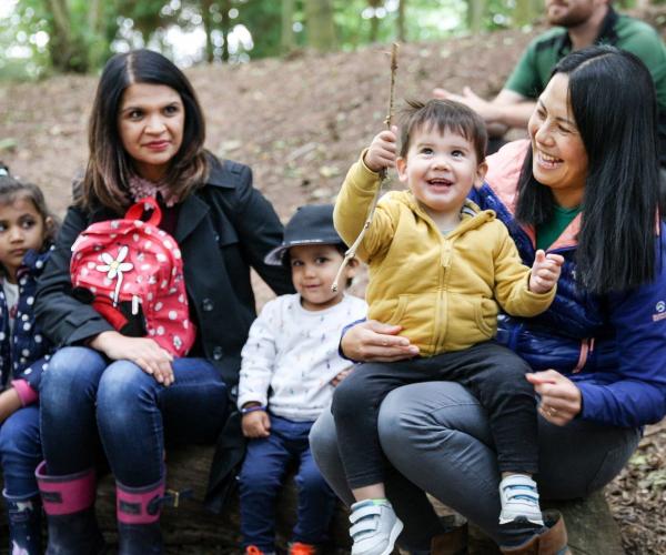 Two women with three small children sitting on a log in the Forest