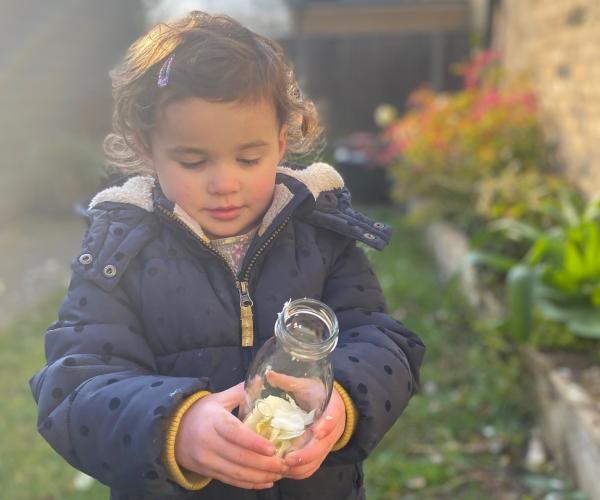 A young foresters holding a glass bottle full of petals