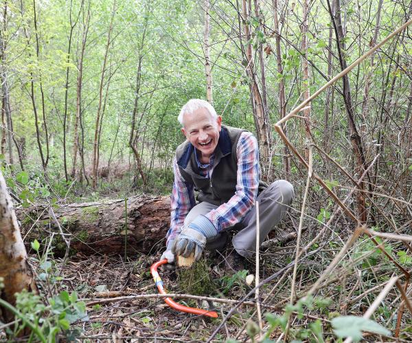 A volunteer sawing back some tree branches in the Forest