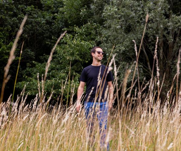 Alexander Sims standing in grassland in the Forest wearing sunglasses