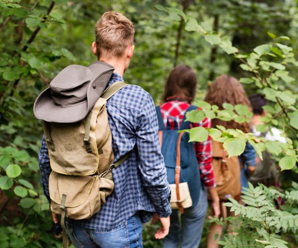 Teenage boy and girls and walking through native broad leaf woodland - Shutterstock.