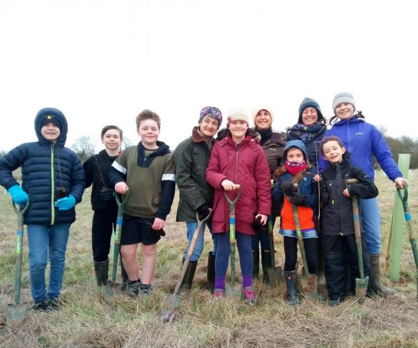 a group of adults and children holding shovels at the bearley community planting event