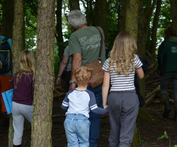 Adults and children walking through a woodland in spring.