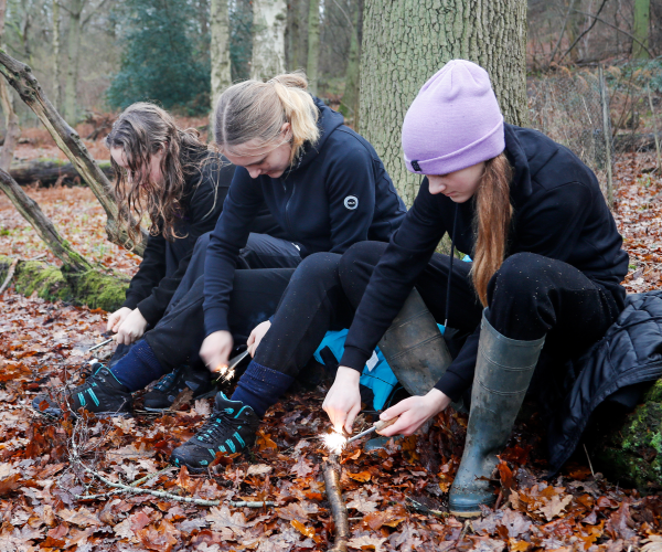 Young foresters undertaking forestry activities whilst sitting on a fallen trunk