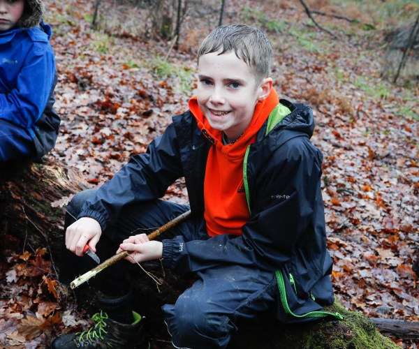 A young forester sitting on the forest floor and smiling