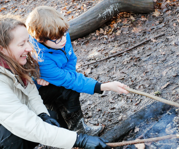 A mother and son toasting marshmellows at the forest