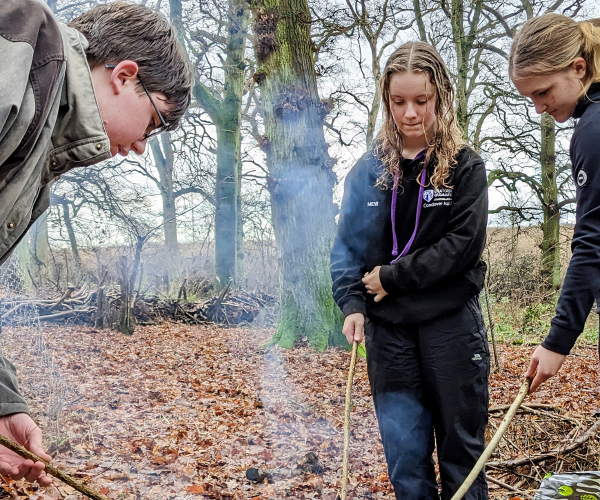 A group of young foresters roasting marsh mellows in the forest