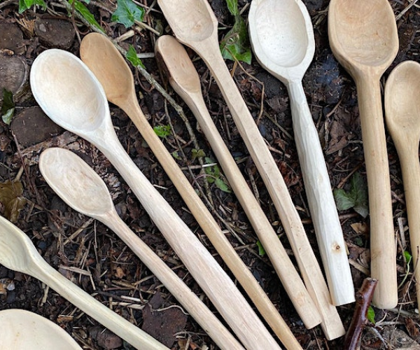 A group of newly made spoons laid out from a previous workshop