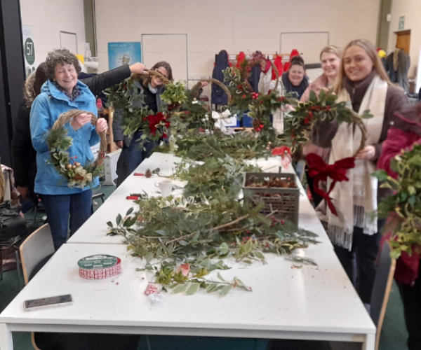 A group of previous attendees showing their newly made Christmas wreaths