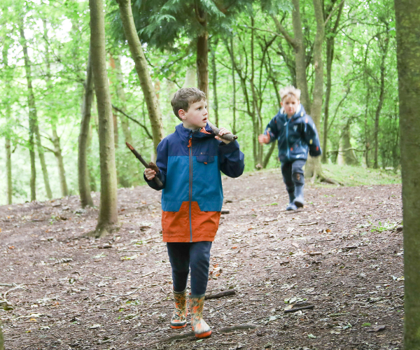 A couple of children running and exploring through the woods together
