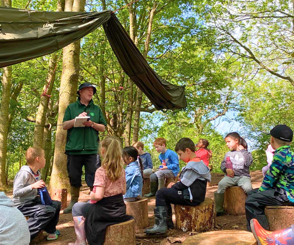 Phil, Senior Outdoor Teacher, teaching a class of children on a summers day