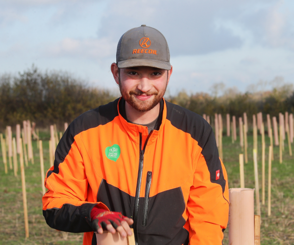 Member of our Forestry team, Hugo, is standing smiling at the camera with a new plantation behind him