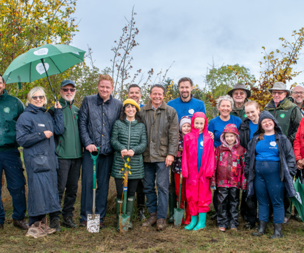 Local MPs Chris Bloore, Manuela Perteghella, and Nigel Huddleston, Chair of Trustees Heather Acton, Chief Executive Andy Parson, Trustees, and volunteers with a newly planted  tree in the Heart of England Forest