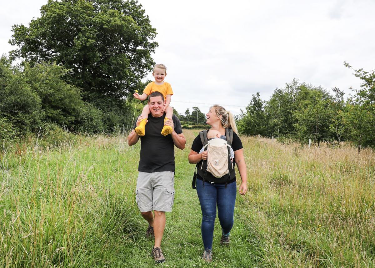 Man and woman walking in the woods with their young daughter and baby