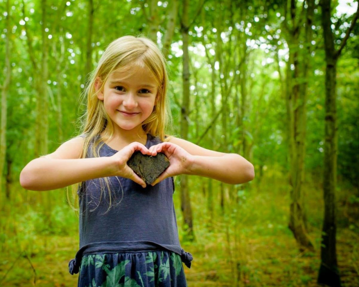 Young girl standing in the Forest making a heart shape with her hands