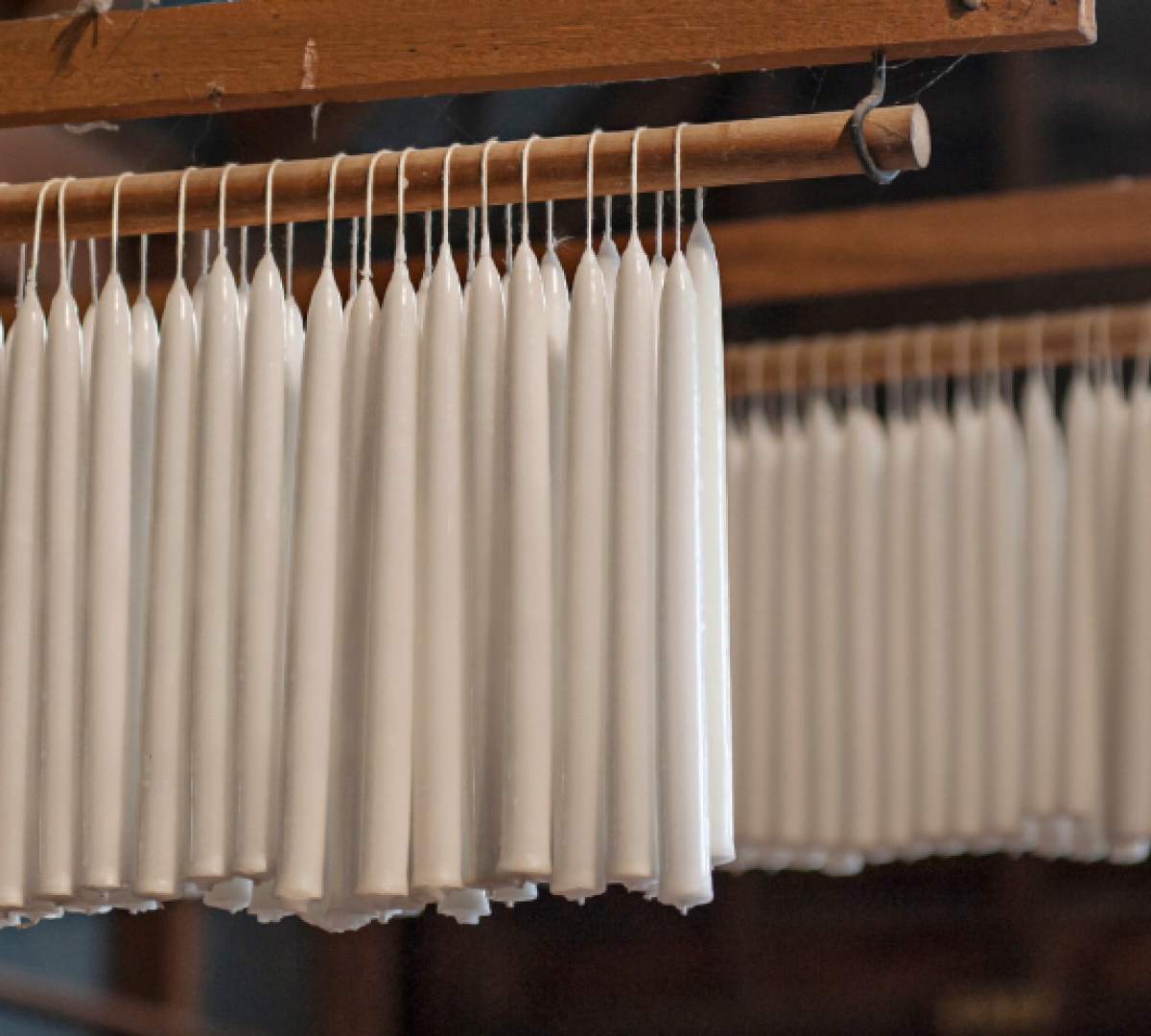 wax candlesticks hanging to dry on a wooden beam