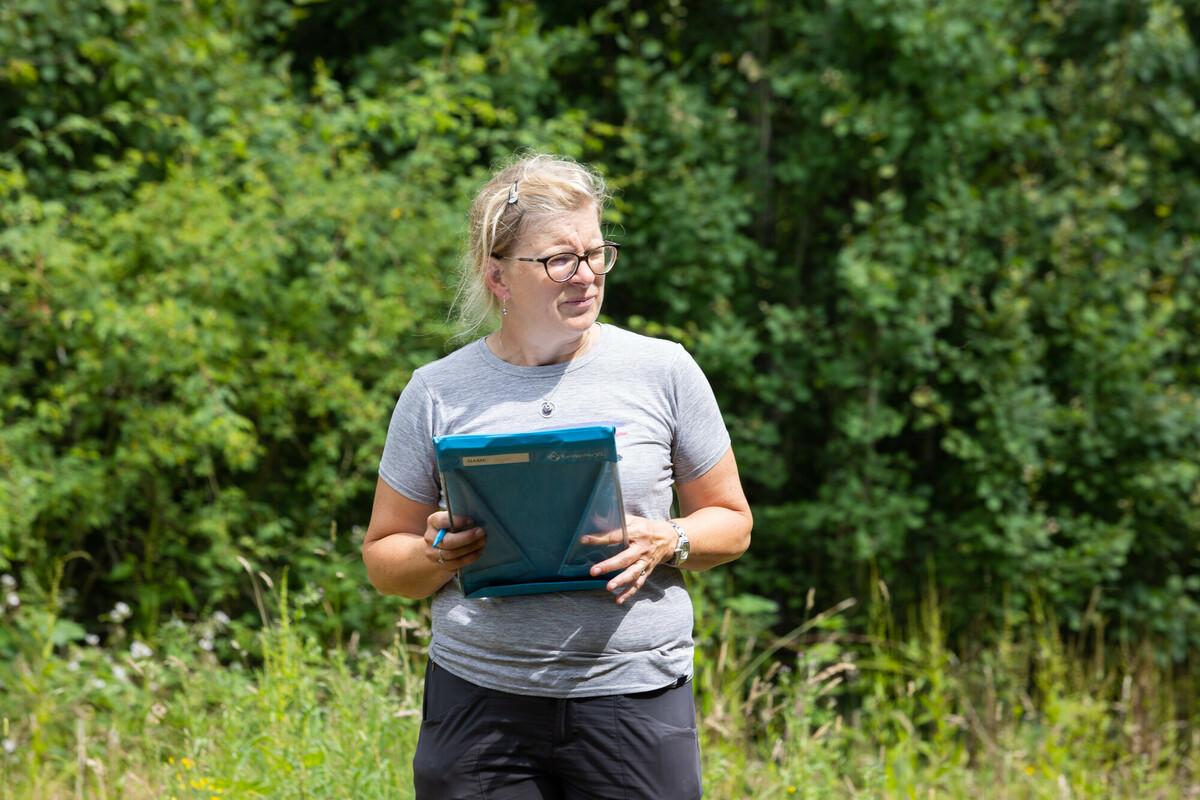 Andrea, Learning and Skills Officer standing outside holding a clip board on a sunny day