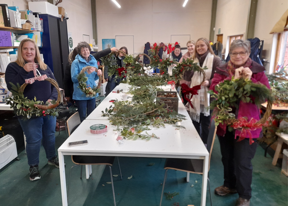 A group of previous attendees holding up their newly made Christmas wreaths