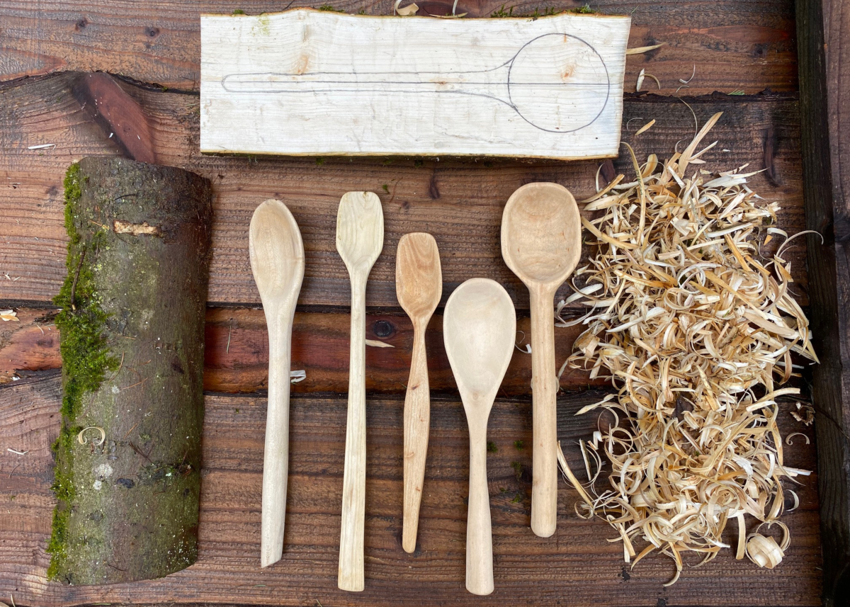 An image showing the various stages of carving a spoon, including the finished spoons in the middle