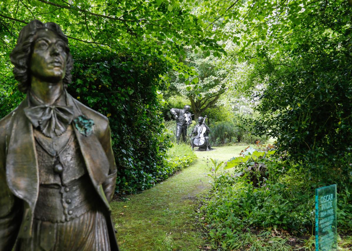 Oscar wild in the fore ground. hedges with lush green leaves in the summer months of the Garden of Heroes and Villains 