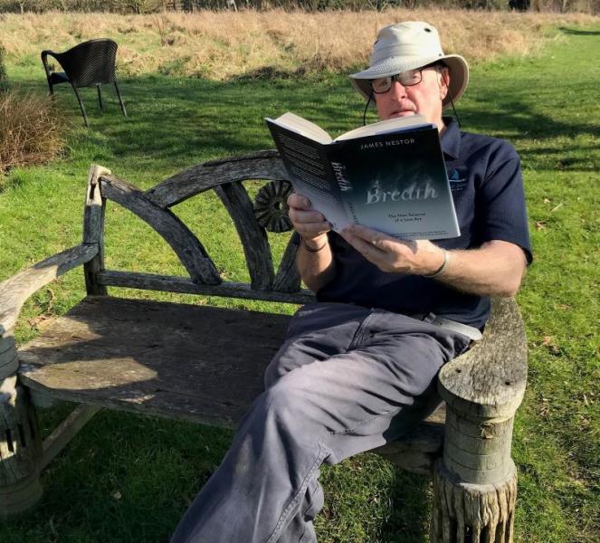 Our Mooring and Caravan Park Manager relaxing on a bench and reading his copy of 'Breath' by James Nestor
