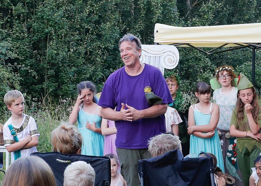 Head Teacher Alex Funch standing in front of the performing children and smiling at the audience of parents