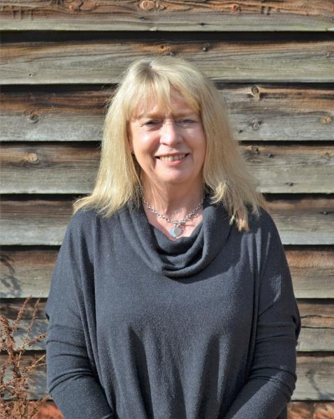 Doreen smiling in front of wooden panelled wall