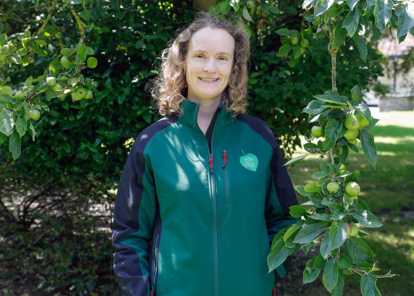 Close up of Sophie wearing a branded jacket and standing with her hands in her pockets