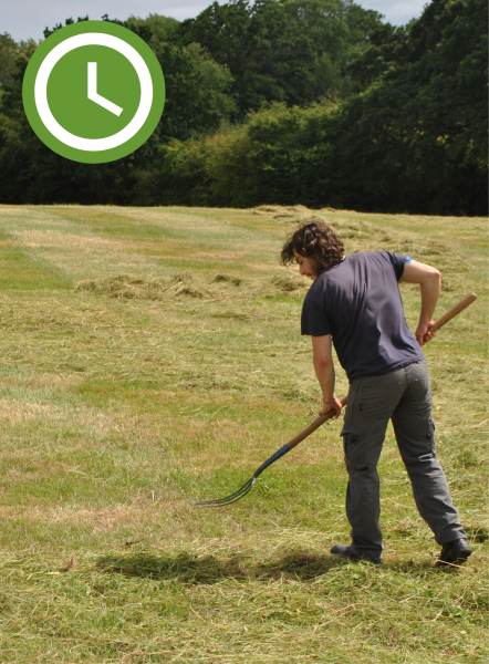 A male volunteer raking grass at Gorcott Hill - A clock graphic in the top left of the image