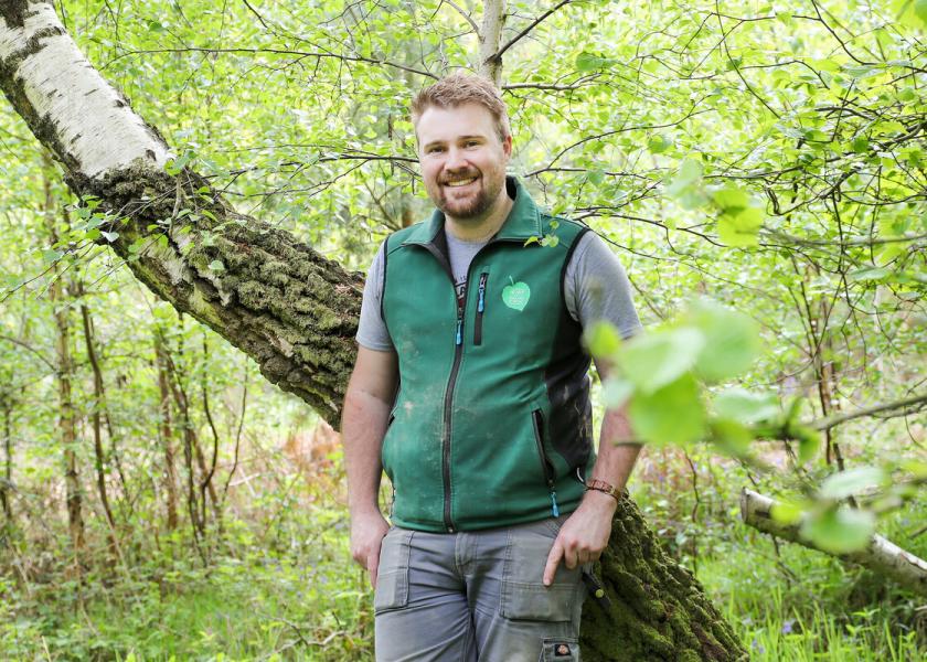 Jonathan Saunders, Volunteer Manager leaning against a tree smiling at the camera