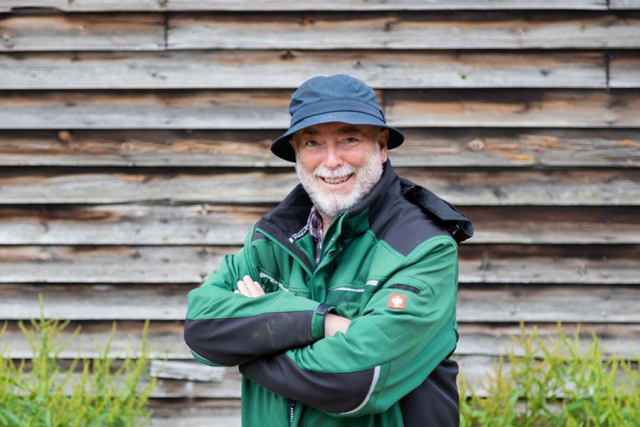 Phil Stickley, Senior Outdoor Teacher standing with his arms crossed in front of a wooden barn