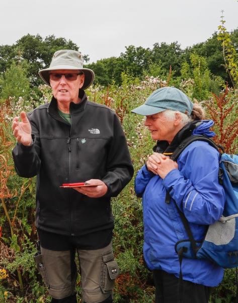 Volunteer Leader Ramsay standing in the Forest explaining butterfly species to a female volunteer standing next to him