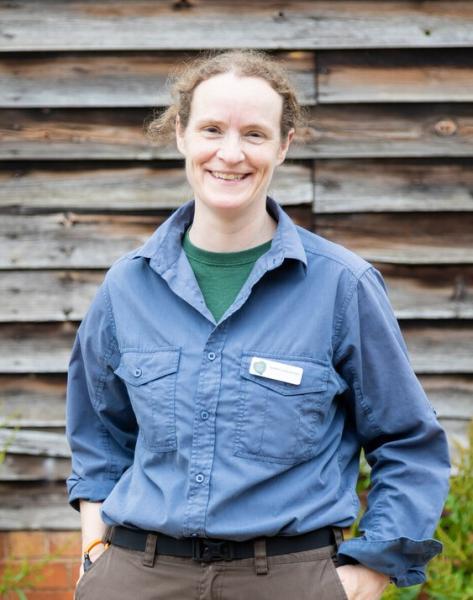 Biodiversity Officer Sophie standing in front of a wooden wall smiling at the camera