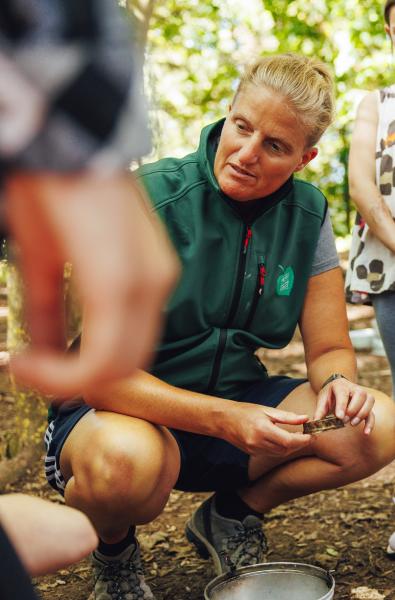 Helena crouching down talking to children in an outdoor lesson