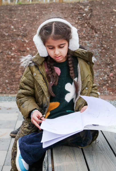 A schoolchild writing in a notebook after an outdoor learning session.