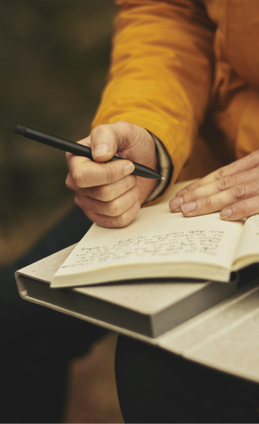 A hand writing in a note book - The person is outside