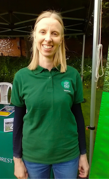 Abby wearing a branded shirt at an event smiling in the camera