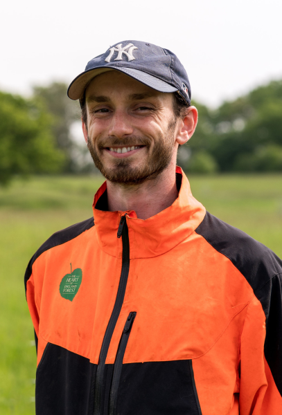 A head and shoulders shot of Wilf smiling with mature trees in the background